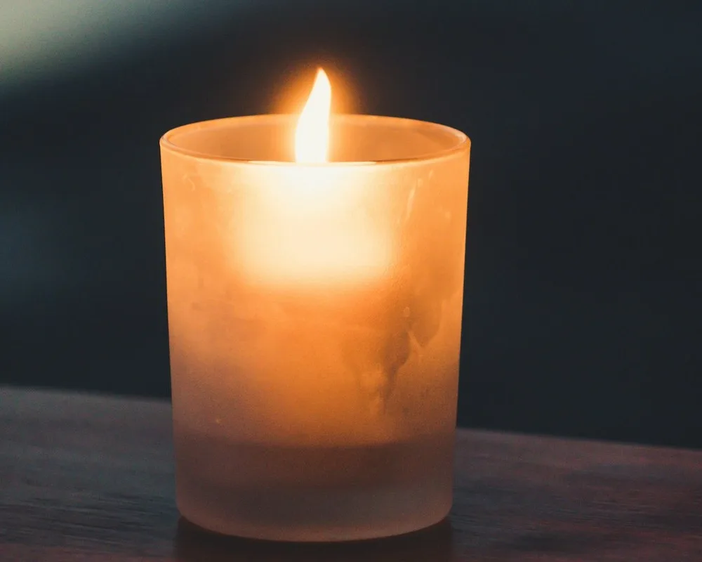 A candle glowing softly in a frosted glass