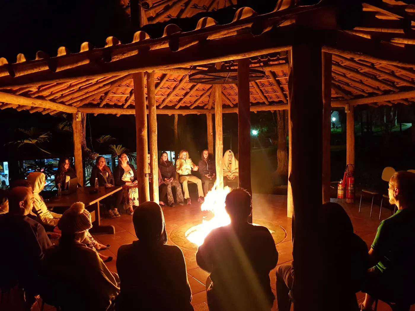 Evening circle around a fire under a wooden pergola