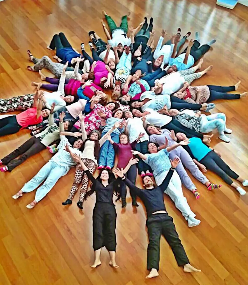A group lying on the floor in a star shape, arms raised